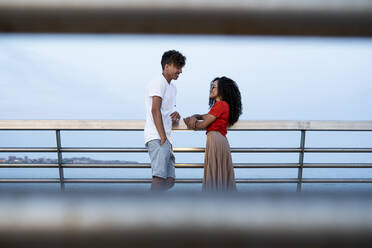 Flirtendes Paar auf Brücke stehend, im Gespräch - RCPF00077