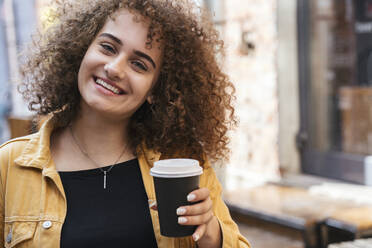 Porträt eines glücklichen Teenagers mit Kaffee zum Mitnehmen - VPIF01539