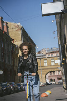 Porträt eines lächelnden Teenager-Mädchens beim Rollerfahren in der Stadt - VPIF01562