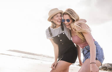 Two girlfriends having fun, walking on the beach - UUF19021