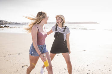 Zwei Freundinnen haben Spaß, laufen und springen am Strand - UUF19023