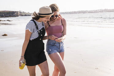 Zwei Freundinnen haben Spaß, gehen am Strand spazieren und machen Smartphone-Selfies - UUF19032