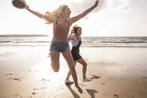 Zwei Freundinnen haben Spaß, laufen und springen am Strand - UUF19040