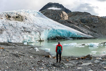 Rear view of hiker against melting glacier - CAVF64837