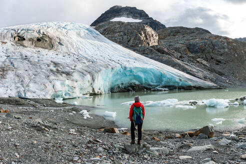 Rückansicht eines Wanderers vor einem schmelzenden Gletscher - CAVF64837