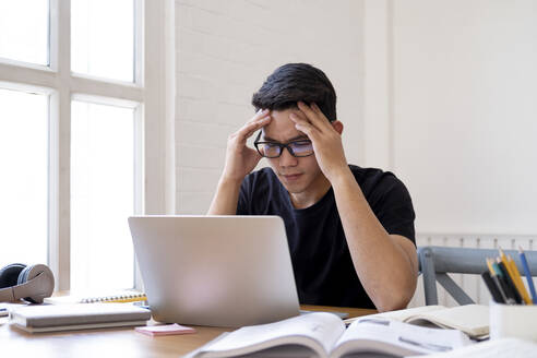 Zweifelnder Schüler, der an Hausaufgaben oder Forschungsarbeiten arbeitet. - CAVF64913