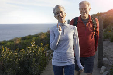 Cheerful senior couple walking on floorboard against sky sunny day - CAVF64953