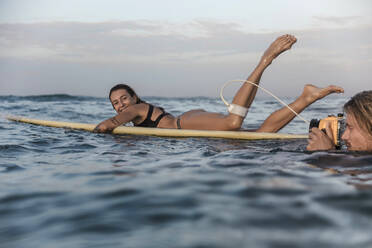 Glückliches Paar mit Surfbrett und Kamera im Meer - CAVF65025