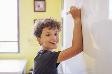 Portrait of smiling boy drawing on a whiteboard - DLTSF00213