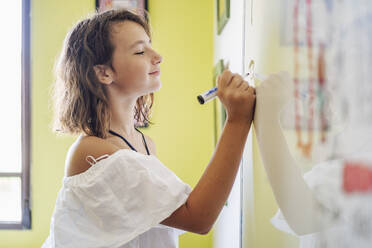 Porträt eines lächelnden Mädchens, das auf einem Whiteboard zeichnet - DLTSF00224