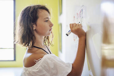 Porträt eines lächelnden Mädchens, das auf einem Whiteboard zeichnet - DLTSF00225