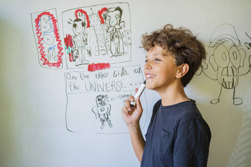 Porträt eines glücklichen Jungen, der auf einem Whiteboard zeichnet - DLTSF00229