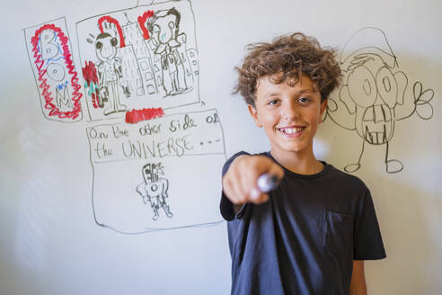 Porträt eines glücklichen Jungen vor einer Zeichnung auf einem Whiteboard - DLTSF00231