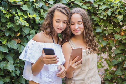 Junge Mädchen mit Smartphone auf Efeu Hintergrund, lizenzfreies Stockfoto