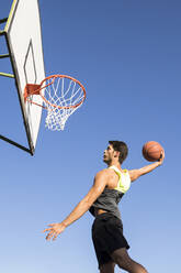 Man jumping high and throwing ball in hoop - ABZF02610