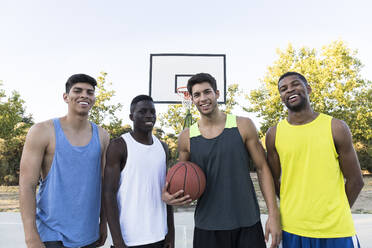 Multiethnische Gruppe von Männern in Sportkleidung mit Basketball auf einem Sportplatz - ABZF02621