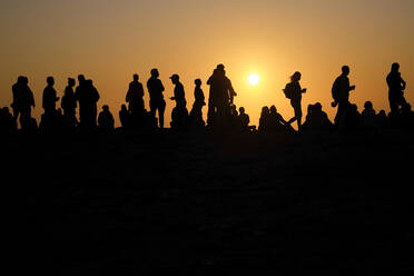 Portugal, Algarve, Silhouetten von Menschen, die sich vor der untergehenden Sonne am Kap Saint Vincent entspannen - MRF02157