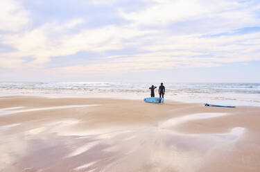 Portugal, Algarve, Silhouettes of two surfers standing on Cordoama beach - MRF02176