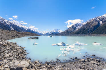 New Zealand, South Island, Rocky shore of Tasman Lake with icebergs, glacier and mountain backdrop - SMAF01573