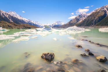 New Zealand, South Island, Rocky shore of Tasman Lake with icebergs, glacier and mountain backdrop - SMAF01576