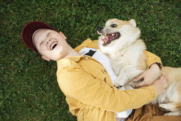 Junge mit Welsh Corgi Pembroke auf der Wiese liegend - VPIF01587