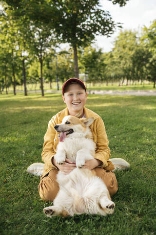 Boy with Welsh Corgi Pembroke in a park stock photo