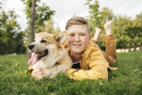 Junge mit Welsh Corgi Pembroke in einem Park - VPIF01595