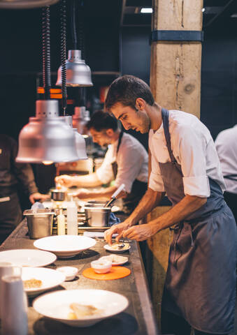 Chef serving food on plates in the kitchen of a restaurant stock photo