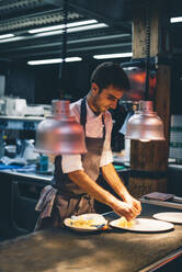 Koch serviert Essen auf Tellern in der Küche eines Restaurants - CJMF00103
