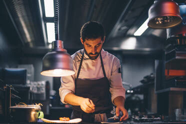 Koch serviert Essen auf Tellern in der Küche eines Restaurants - CJMF00105