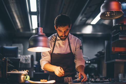 Chef serving food on plates in the kitchen of a restaurant - CJMF00105