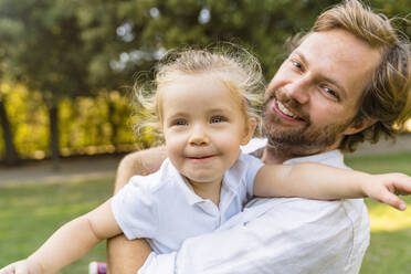 Happy father playing with little daughter in a park - MGIF00770