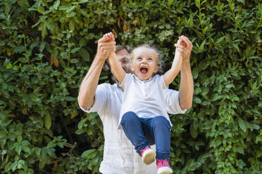 Happy father playing with little daughter in a park - MGIF00771