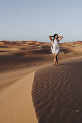 Beautiful young woman walking in the desert, Merzouga, Morocco - DAMF00124