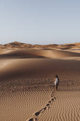Young woman walking in the desert, Merzouga, Morocco - DAMF00127