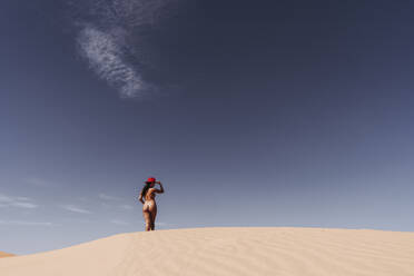 Nude young woman wearing a hat in the desert, Merzouga, Morocco - DAMF00131