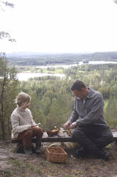 Father and daughter cleaning mushrooms on bench - JOHF02123