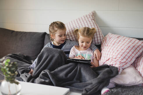 Schwestern mit digitalem Tablet auf dem Sofa - JOHF02215