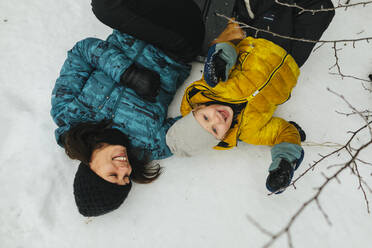 Mutter mit Sohn im Schnee liegend - JOHF02240