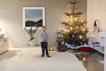 Junge steht neben Weihnachtsbaum im Wohnzimmer - JOHF02255