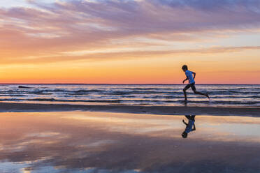 Junge läuft am Strand bei Sonnenuntergang - JOHF02366