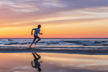 Junge läuft am Strand bei Sonnenuntergang - JOHF02367