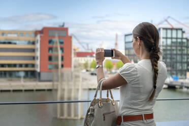 Woman on balcony taking picture - JOHF02434