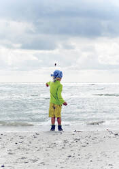 Child throwing stones on beach - JOHF02487