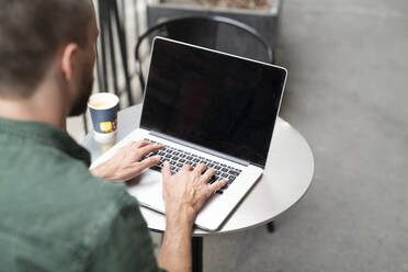 Man using laptop in outdoor cafe - JOHF02522