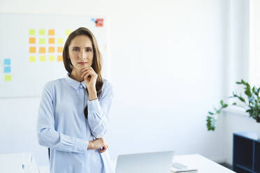 Portrait of confident young businessowman standing in office looking at camera - BSZF01469