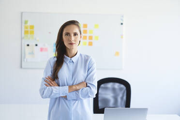 Portrait of confident businesswoman looking at camera with crossed arms in office - BSZF01470