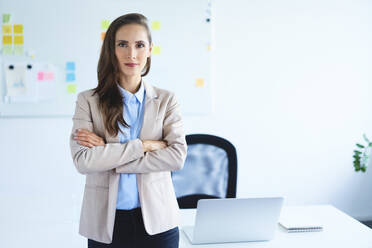 Confident young businesswoman standing in office looking at camera - BSZF01474