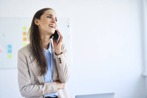 Cheerful businesswoman talking on phone in office stock photo