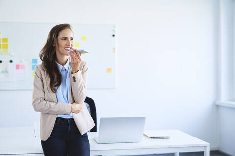 Young woman leaning on desk in office during phone call stock photo